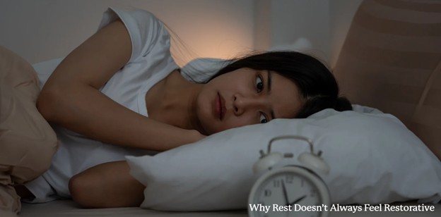 Woman awake in bed, thoughtful expression.